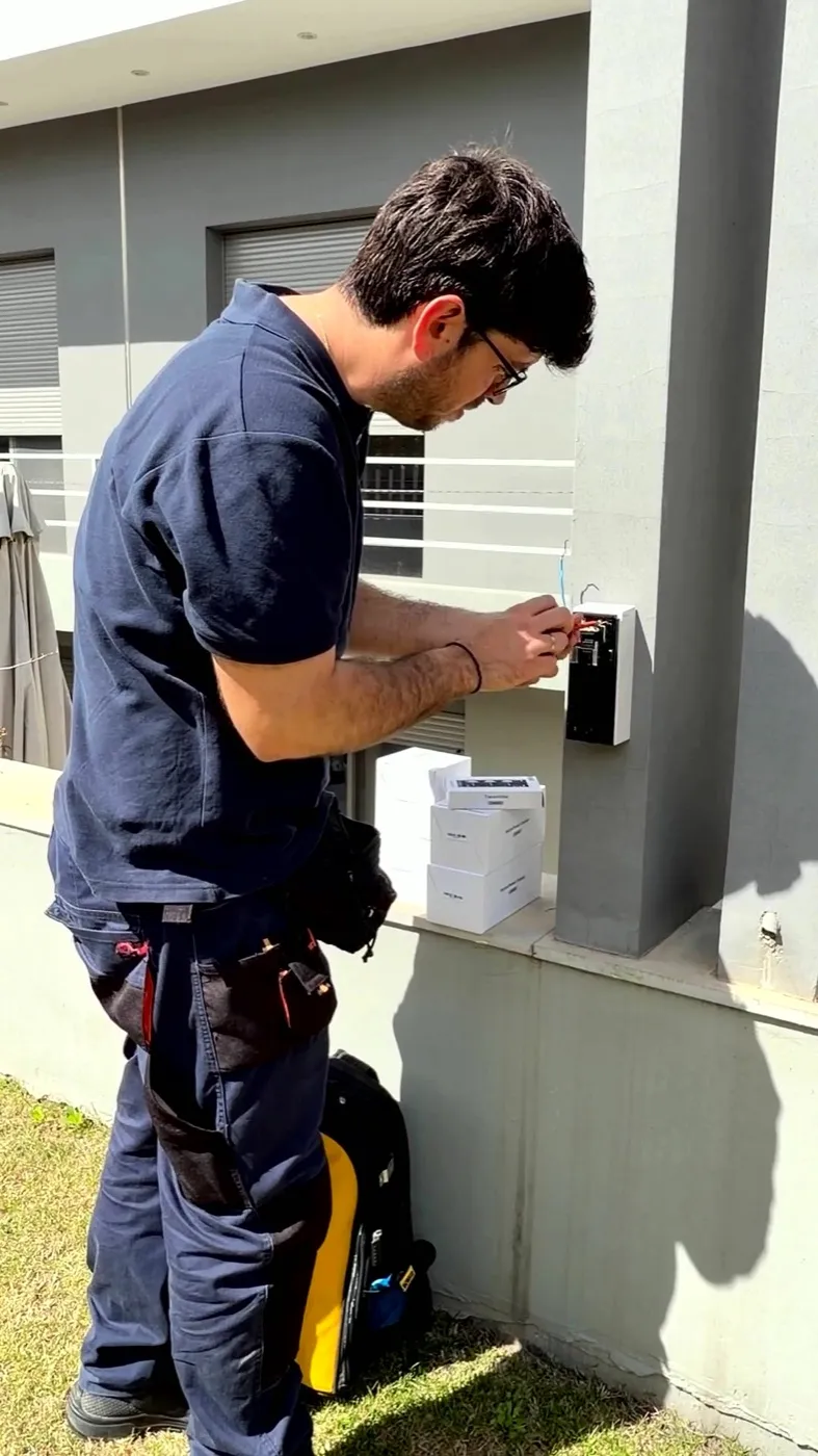 AT Security technician wiring an Ajax transmitter enclosure to integrate an Optex detector into the Ajax ecosystem